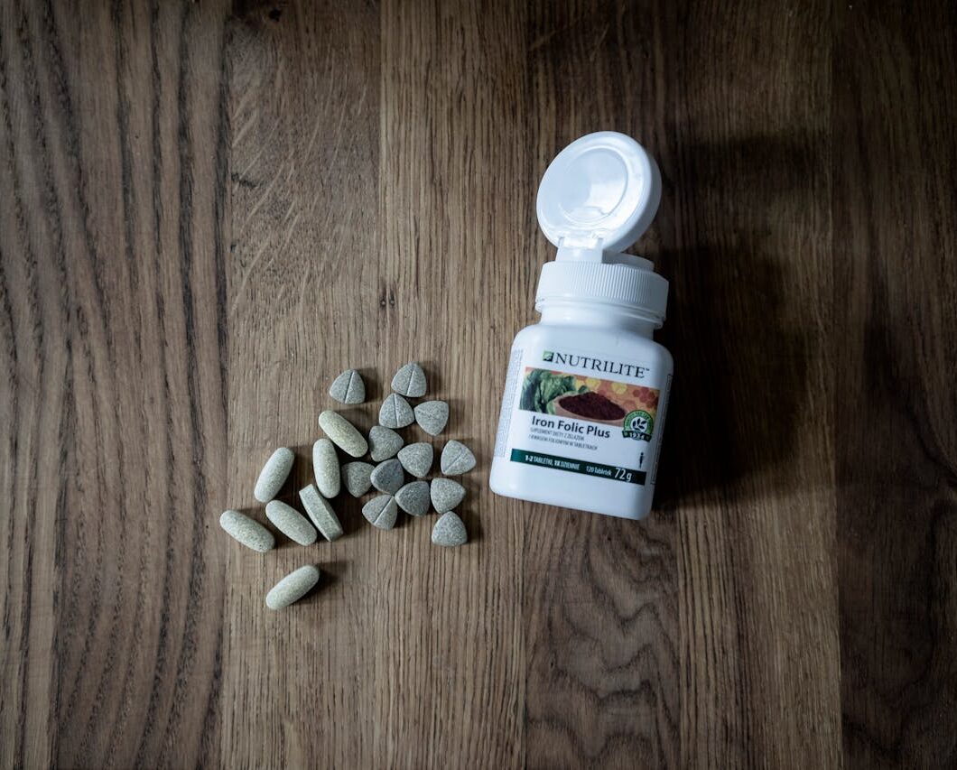 A bottle of folic acid supplements on a table with a glass of water.